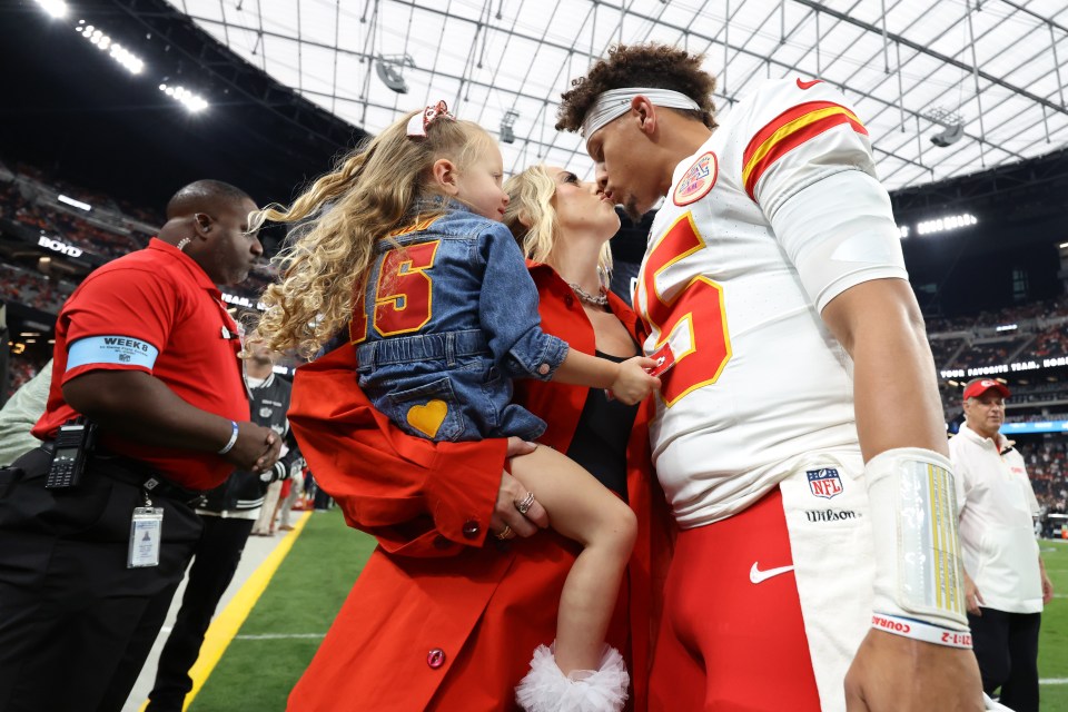 Patrick Mahomes kisses his wife while their daughter watches.