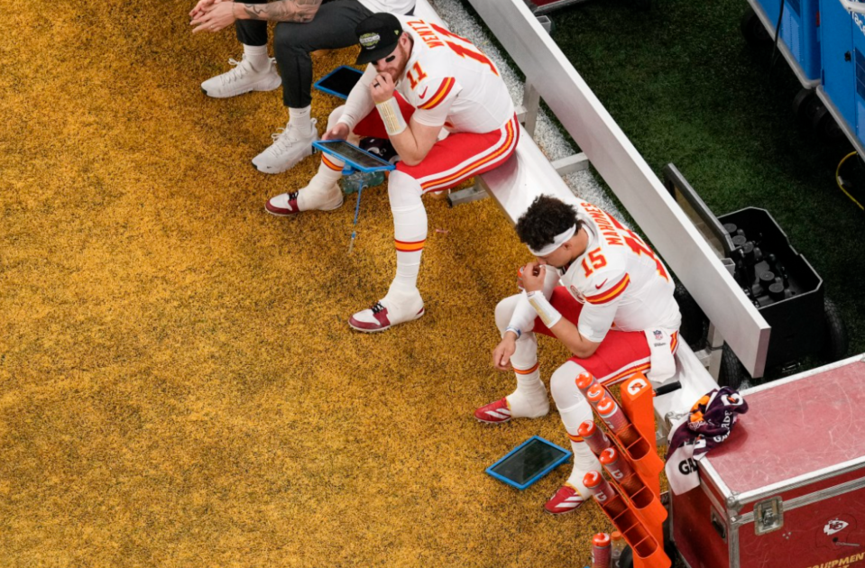 Kansas City Chiefs players on the sidelines reviewing game strategy.